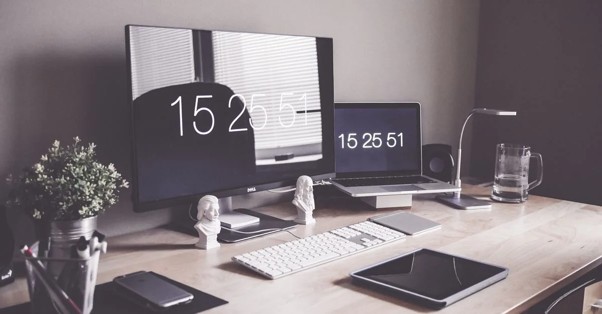 Configuración de escritorio organizada con monitores, laptop y accesorios de oficina para la productividad.