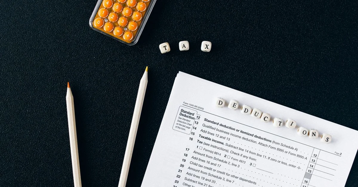 Composición de formularios fiscales, lápices y calculadora sobre fondo negro, enfatizando deducciones fiscales.