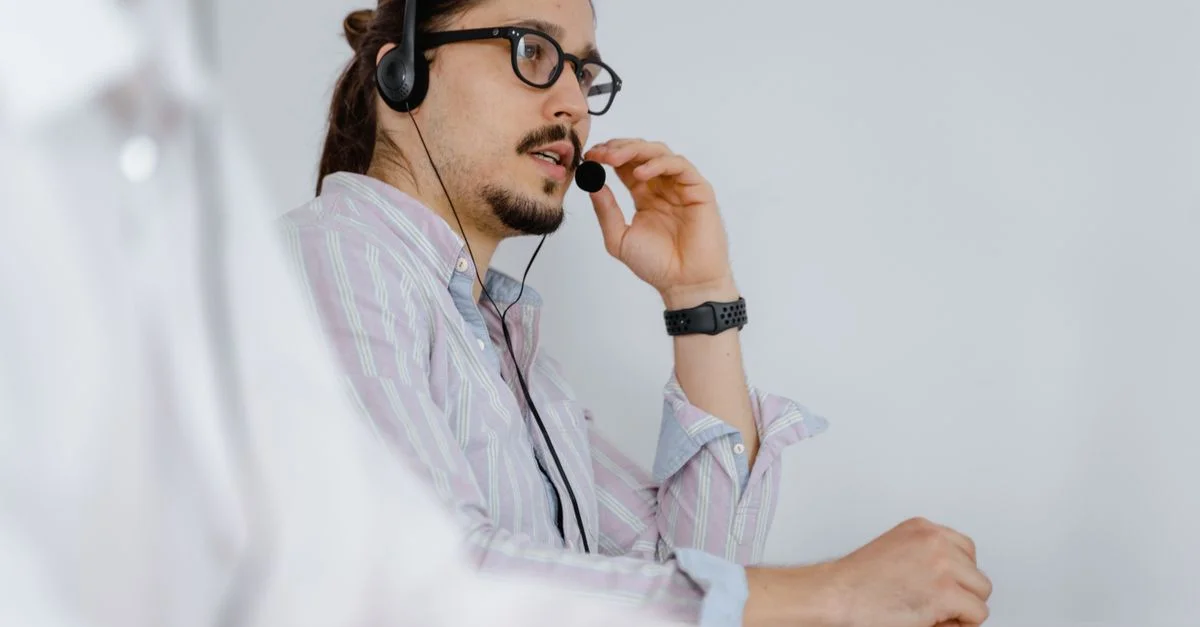 Agente de servicio al cliente enfocado hablando con un auricular en un entorno de oficina moderno.
