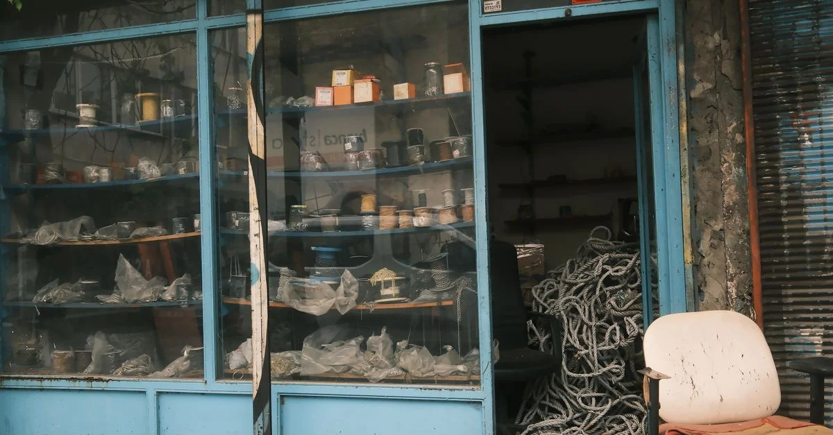 Una ferretería rústica con un aire vintage, que exhibe diversos artículos a través de una vitrina de cristal y una puerta abierta.
