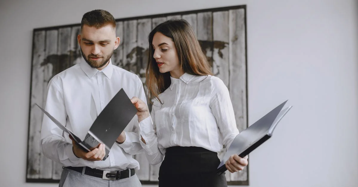 Dos colegas en una oficina moderna revisando documentos juntos.