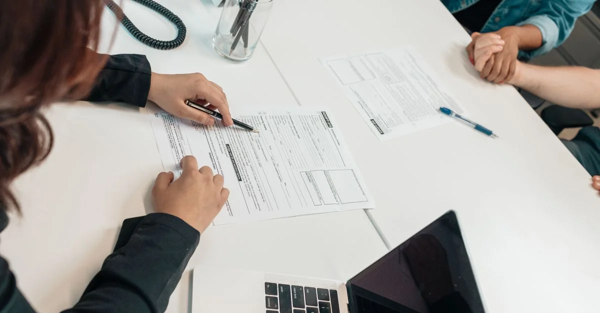 Una reunión profesional con firma de documentos en un escritorio, centrada en el trabajo en equipo.