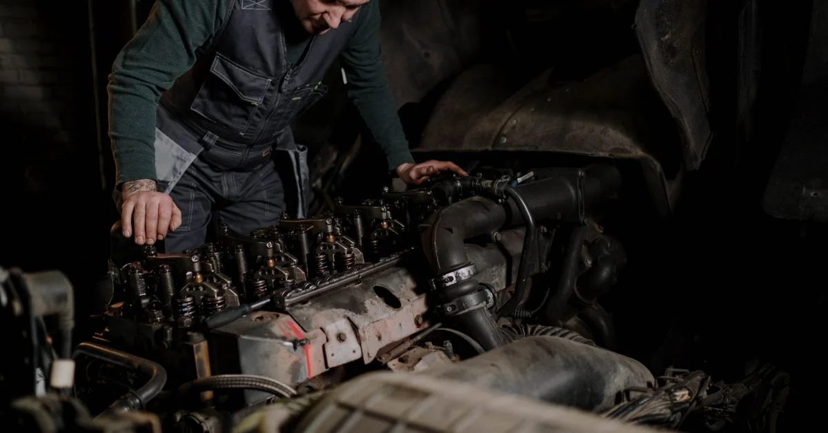 Mecánico enfocado en la reparación de motores de vehículos en un taller interior.