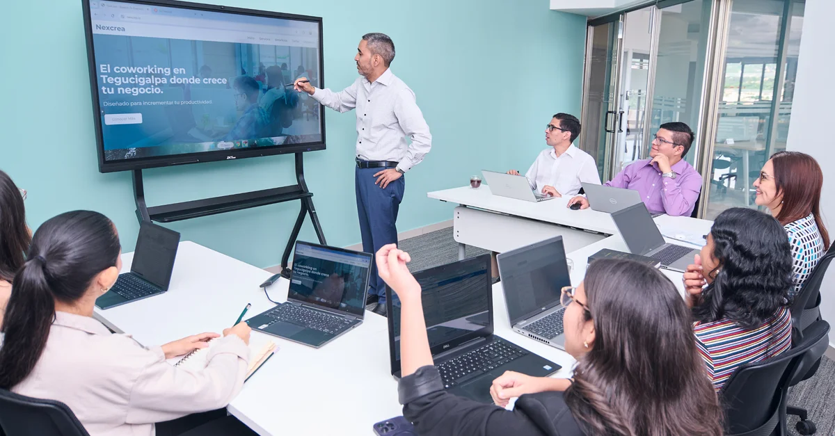 Equipo profesional realizando una presentación de negocios con computadoras portátiles y una pantalla de proyector.