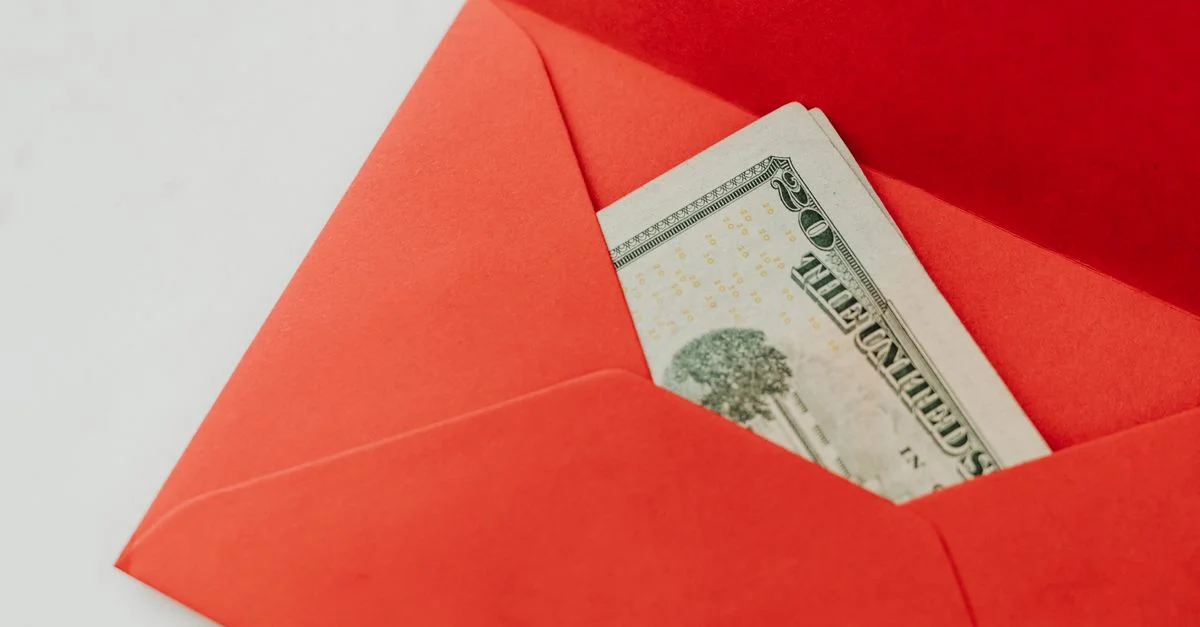 Un sobre rojo que contiene billetes de dólares estadounidenses, simbolizando riqueza y regalo.