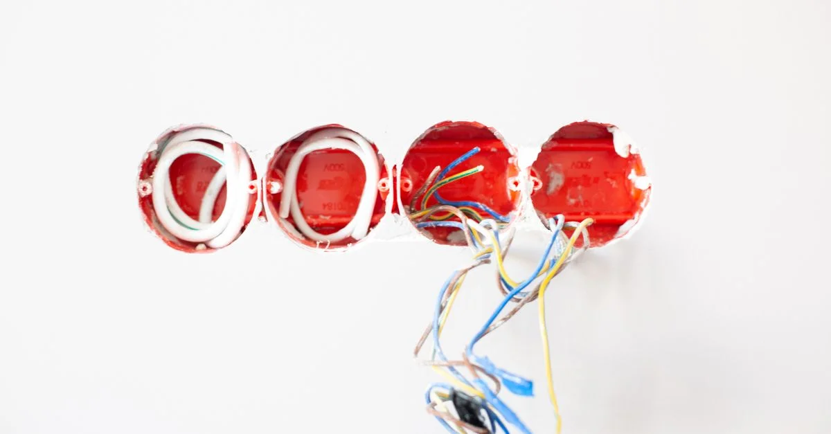 Primer plano de cableado eléctrico expuesto en enchufes listos para instalar. Ideal para contextos de mejora del hogar.