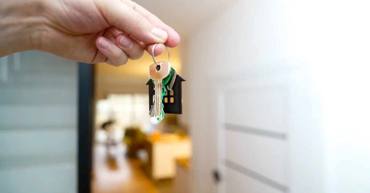 Una mano sosteniendo las llaves de la casa dentro de un apartamento moderno, simbolizando la nueva propiedad o alquiler.