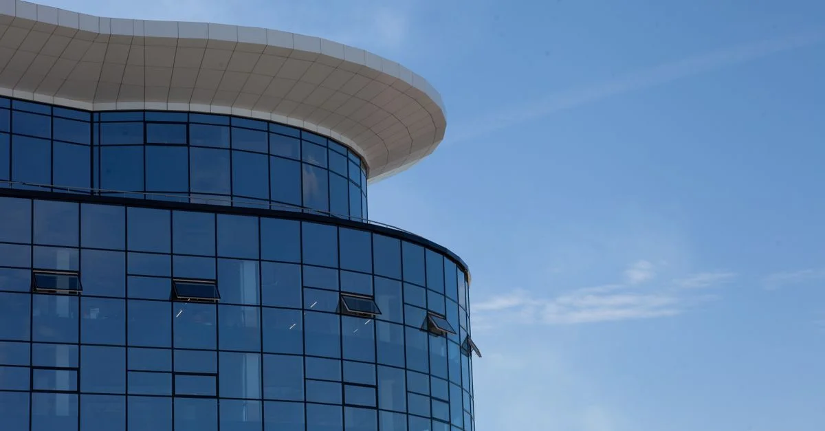 Acercamiento de una fachada de edificio de vidrio moderno contra un cielo despejado.