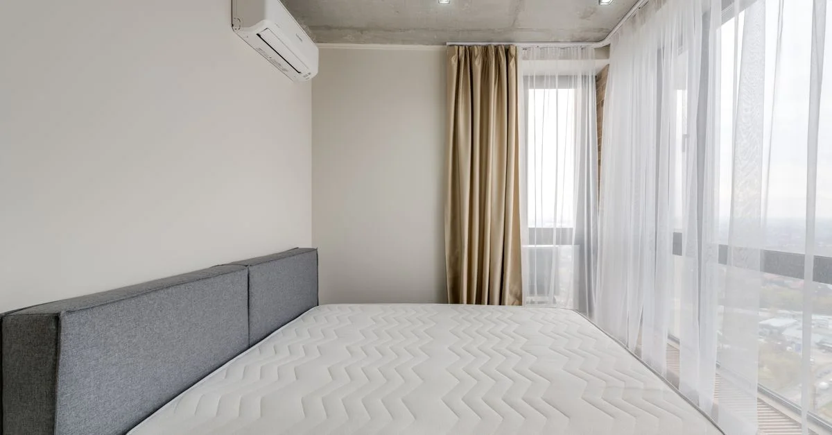 Amplio dormitorio moderno con un colchón limpio y grandes ventanas para luz natural.