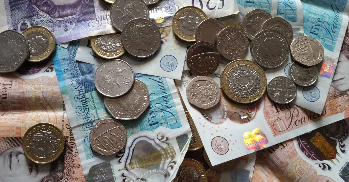 Primer plano de varias monedas y billetes de libra británica que muestran el retrato de la Reina Isabel II.