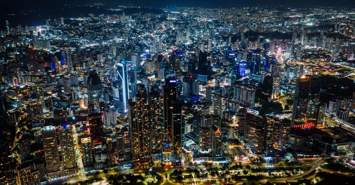 Impresionante toma aérea del vibrante horizonte de la ciudad de Panamá por la noche, un bullicioso paisaje urbano.