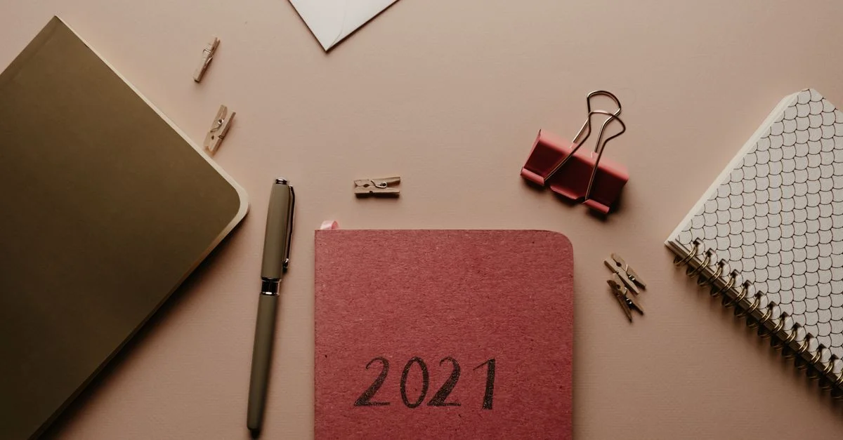 Vista superior de un planificador 2021 con suministros de oficina organizados en un escritorio.