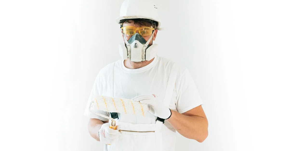 Un pintor profesional con equipo de seguridad sosteniendo un rodillo de pintura, listo para trabajar.