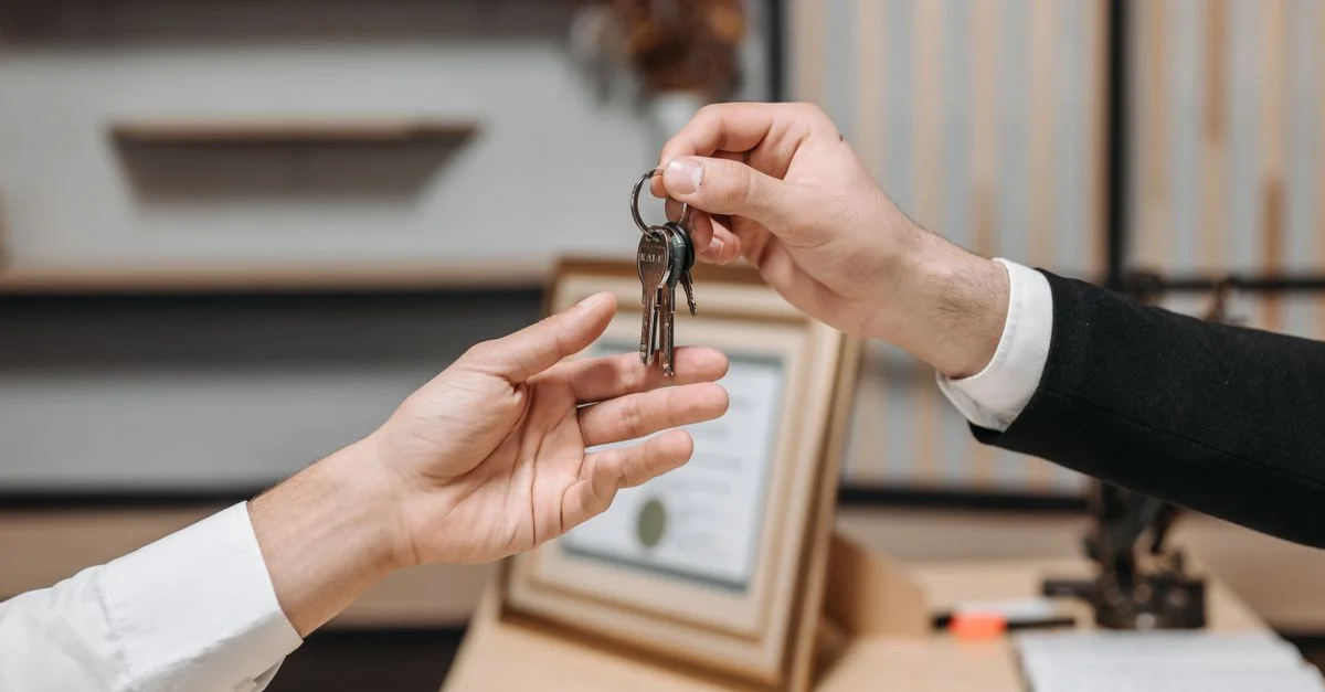 Vista detallada de manos intercambiando llaves en un entorno de oficina profesional, simbolizando transacciones inmobiliarias o comerciales.
