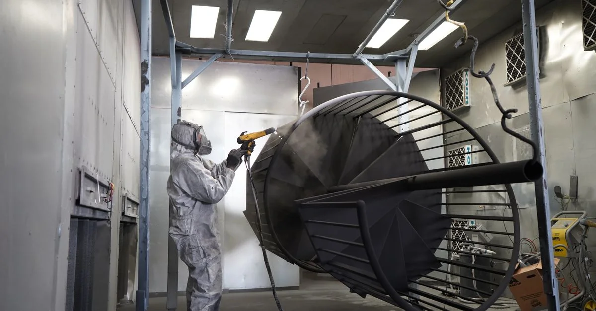 Técnico realizando recubrimiento en polvo sobre estructura metálica en taller industrial.