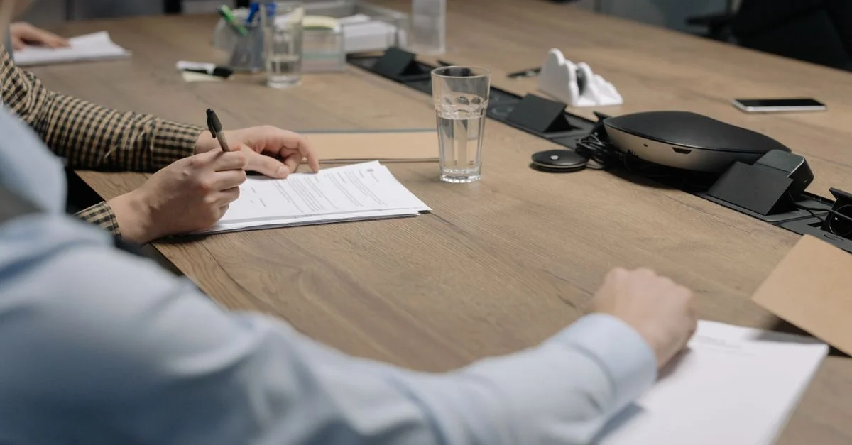 Entorno profesional de una reunión de negocios con individuos firmando documentos en una mesa de conferencias.