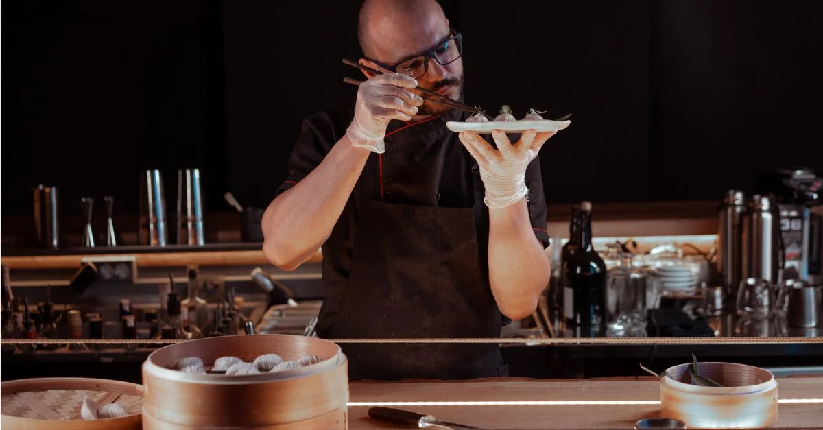 Un chef prepara hábilmente empanadillas en un acogedor entorno de restaurante, enfocándose en los detalles.