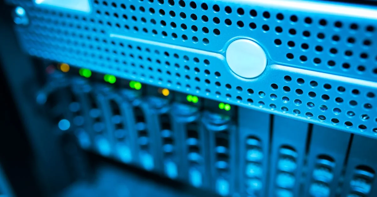Vista enfocada de un moderno rack de servidores de datos con luces parpadeantes en un entorno iluminado con luz azul.
