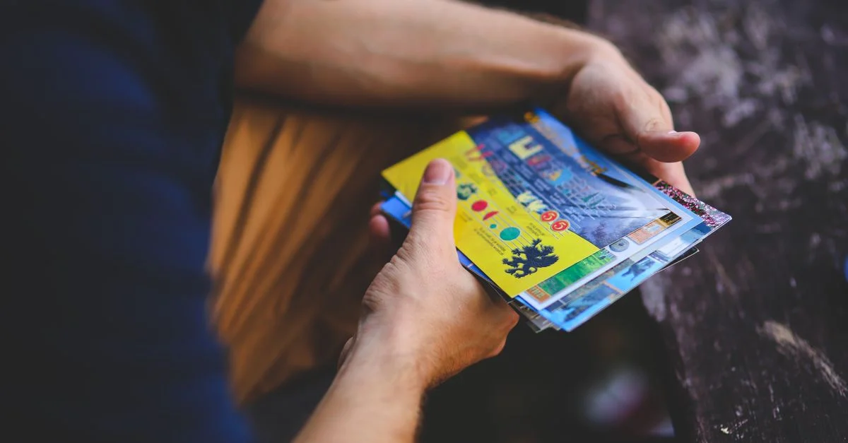Una persona sosteniendo una colección de postales de viaje vibrantes al aire libre.