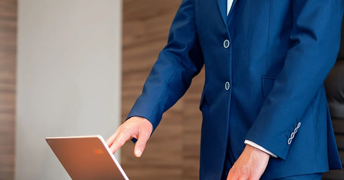 Profesional de negocios en un traje utilizando un laptop en un escritorio en un entorno de oficina.
