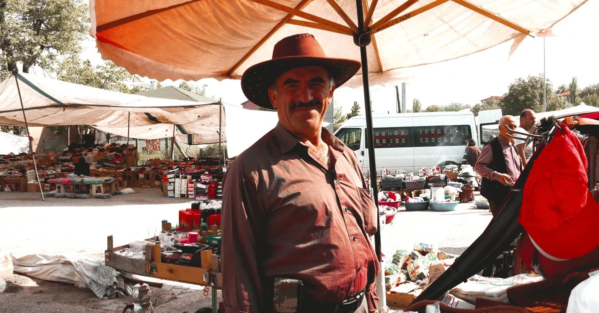 Vendedor sonriente con sombrero en el mercado de Hamamözü en Turquía, mostrando la vida tradicional del bazar.