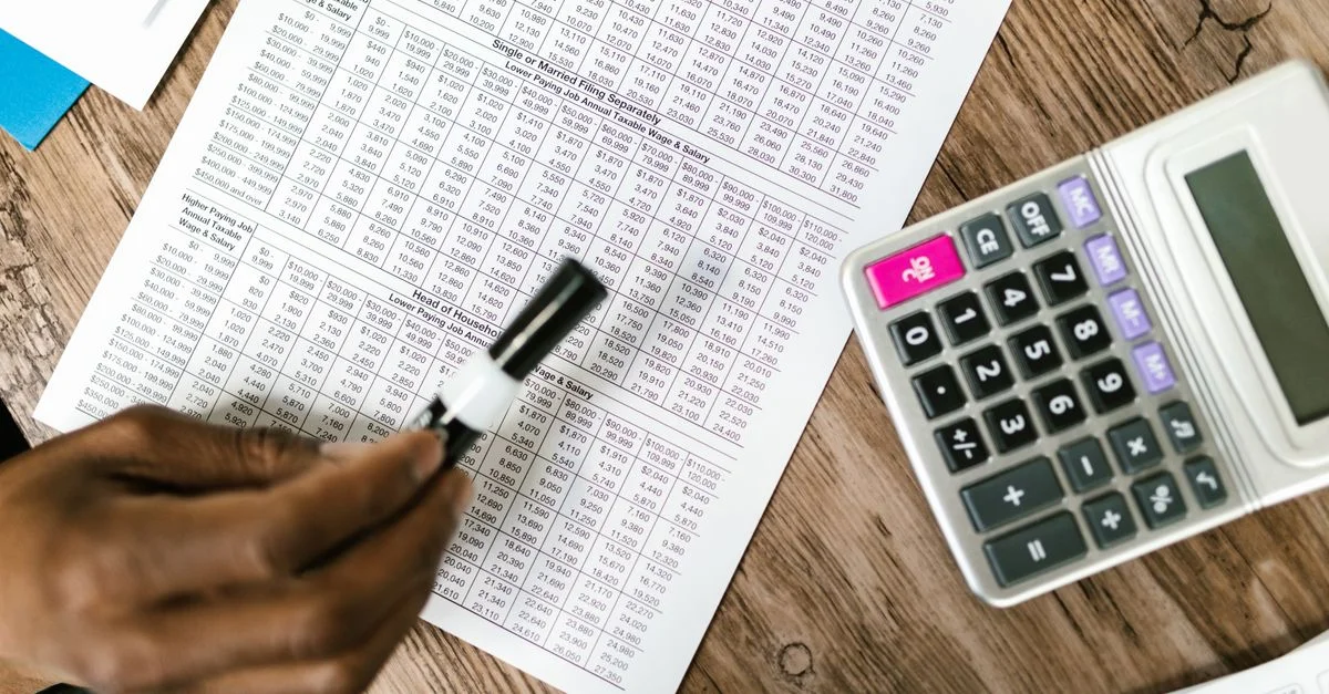 Primer plano de documentos fiscales y calculadora sobre una mesa de madera, destacando el análisis financiero.