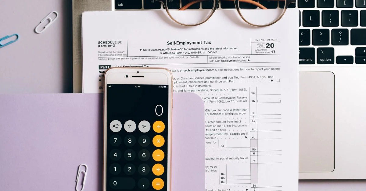 Vista plana de documentos fiscales, calculadora de smartphone y laptop para contabilidad de autónomos.