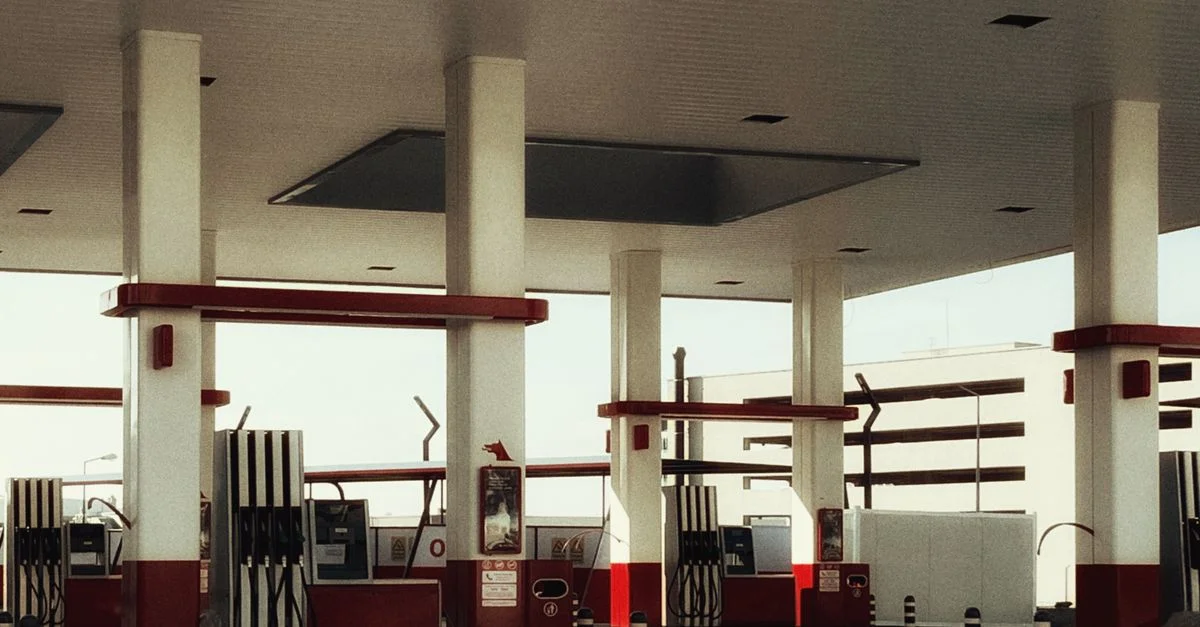 Gasolinera moderna con iluminación brillante, múltiples surtidores de combustible y un diseño distintivo en rojo y blanco.