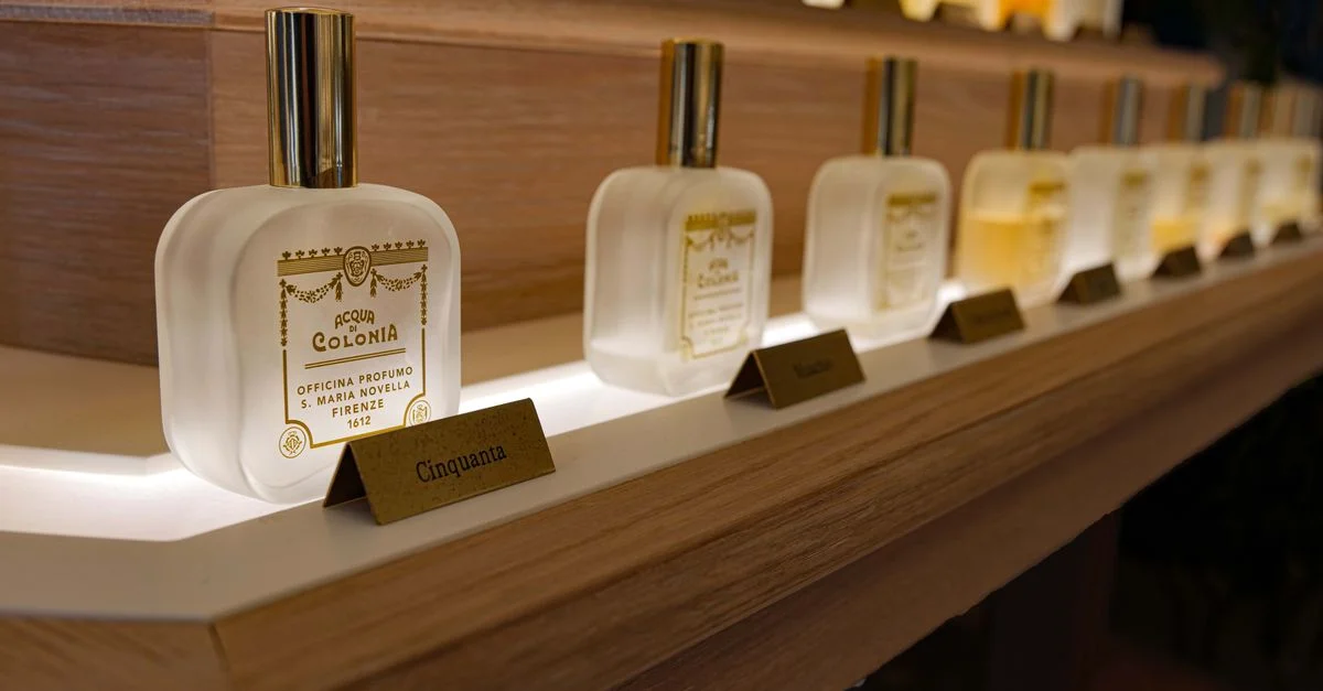 Primer plano de elegantes botellas de perfume de lujo en una estantería de madera con iluminación ambiental.