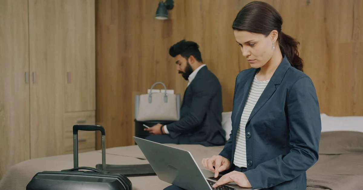 Profesionales de negocios utilizando sus computadoras portátiles en una habitación de hotel, concentrados en el trabajo.