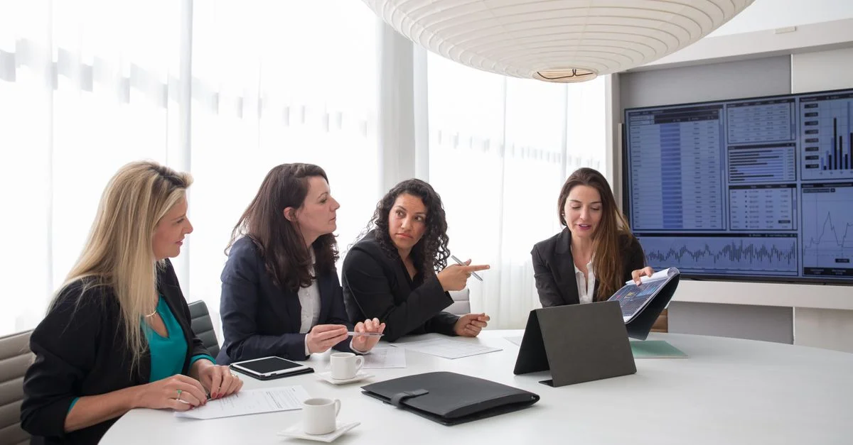 Mujeres de negocios discutiendo informes durante una reunión en un entorno de oficina contemporáneo.
