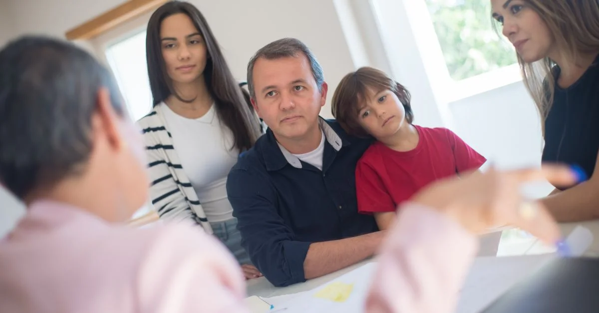 Una familia de cuatro busca asesoramiento de un profesional durante una consulta en interiores en una habitación luminosa.