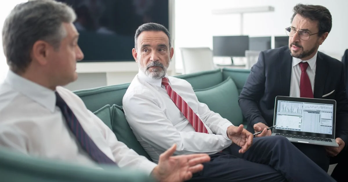 Empresarios discutiendo la estrategia corporativa durante una reunión en un entorno de oficina moderna.