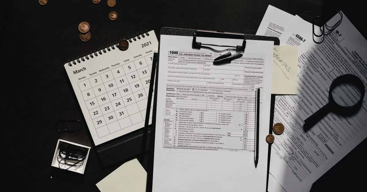 Un espacio de trabajo ordenado que incluye formularios fiscales, calendario, lupa y suministros de oficina para una preparación de impuestos eficiente.