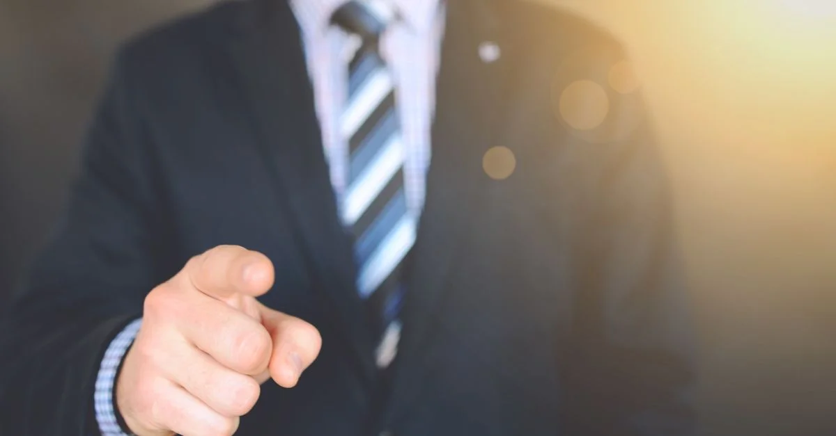 Hombre de negocios seguro en traje apuntando hacia adelante, simbolizando liderazgo y enfoque.