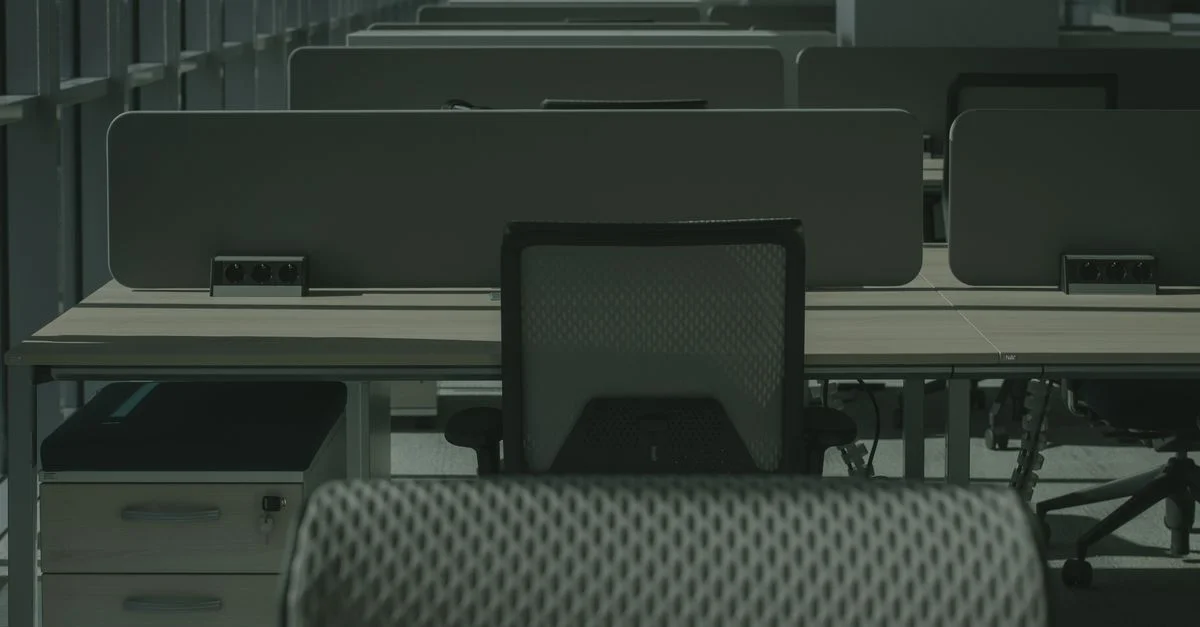 Una oficina moderna y elegante con múltiples escritorios y sillas, mostrando un espacio de trabajo vacío y ordenado.