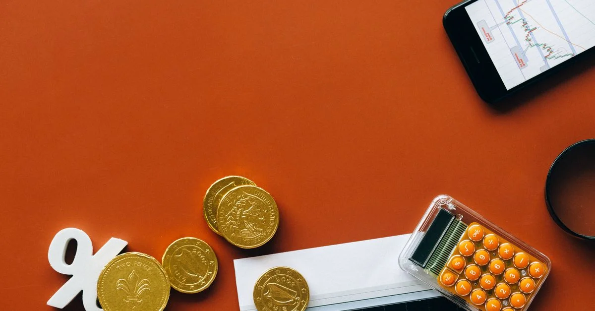 Vista plana que muestra monedas, calculadora y gráficos sobre un fondo rojo para análisis financiero y conceptos de negocio.