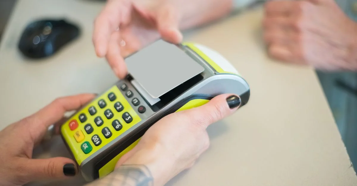 Manos realizando una transacción segura con tarjeta en un terminal de pago, capturando la esencia de las transacciones comerciales modernas.
