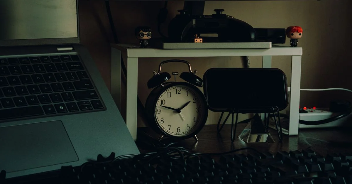 Configuración de escritorio ordenada con un portátil, reloj analógico y decoración de escritorio en un entorno moderno de trabajo en casa.