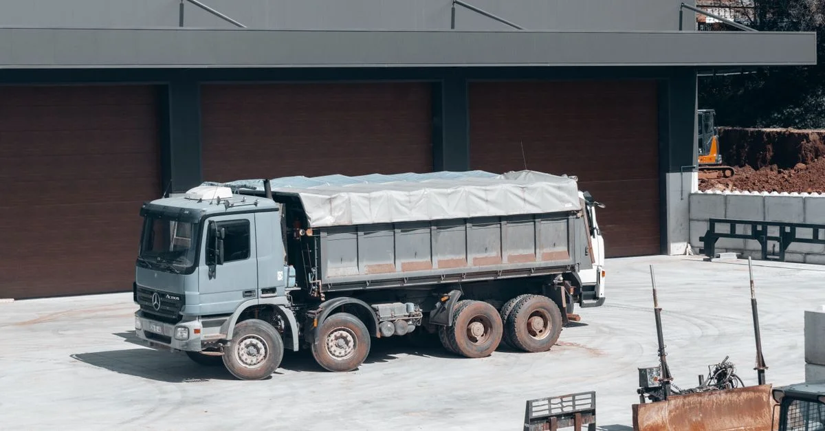 Un gran camión volquete estacionado en una obra industrial cerca de un edificio.