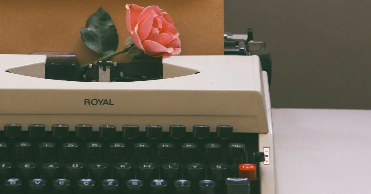Una máquina de escribir antigua sostiene una rosa rosa y una carta, evocando nostalgia y romance.
