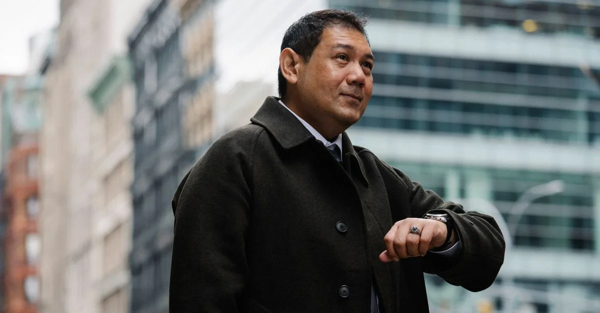 Empresario seguro mirando su reloj en la calle urbana, listo para una reunión.