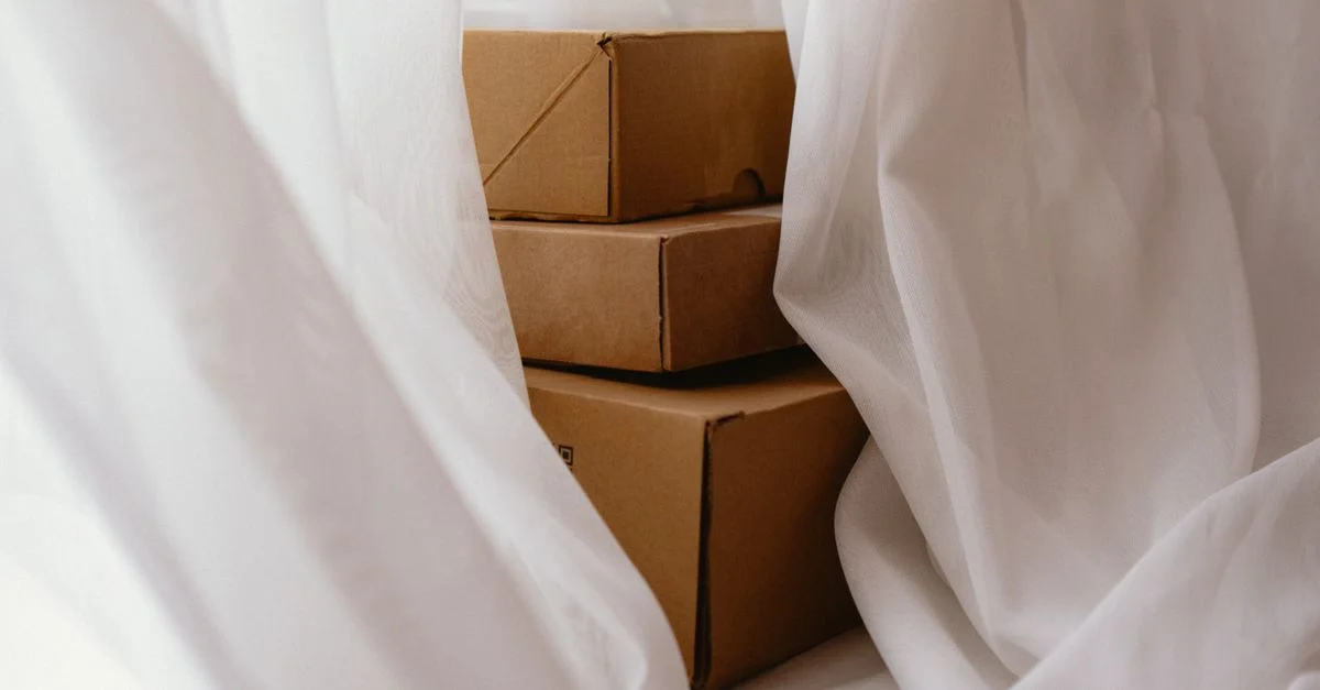 Cajas de cartón ocultas tras una cortina blanca vaporosa, creando una escena interior acogedora.