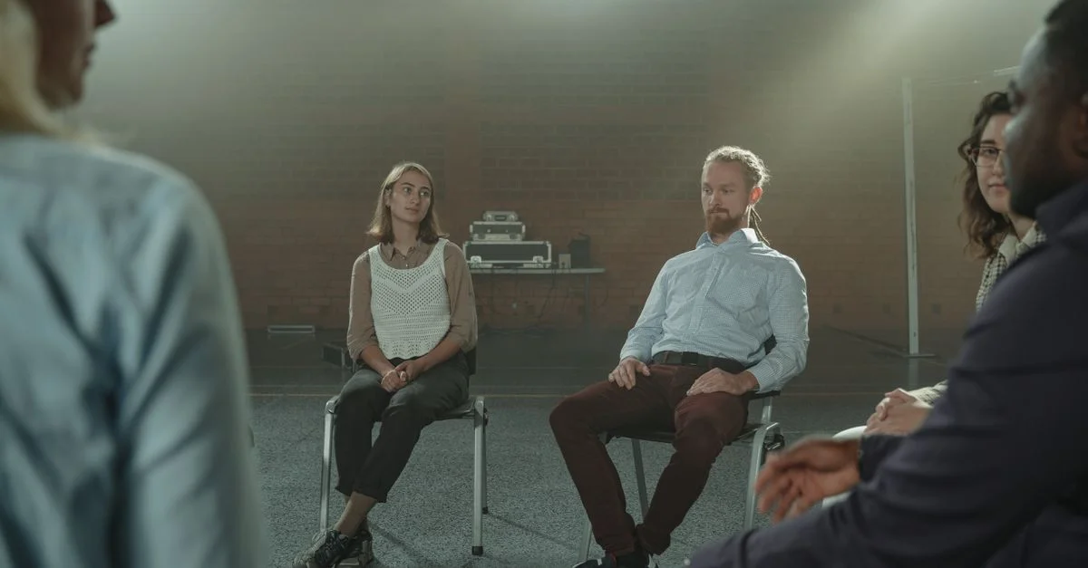 Un grupo diverso de adultos participando en una conversación reflexiva en el interior.