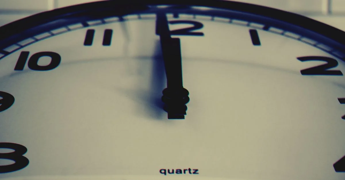Toma de close-up detallada de un reloj de pared que muestra la manecilla de la hora a la medianoche, destacando el concepto de tiempo.
